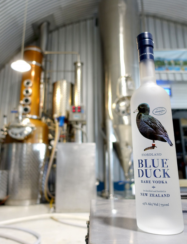 Blue Duck Vodka in front of distilling equipment